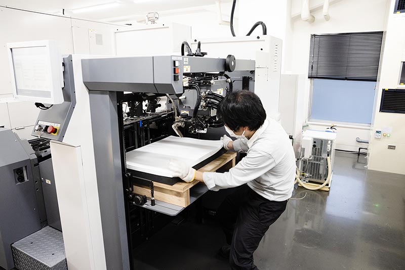 高精細デジタル印刷機に紙をセットしている様子